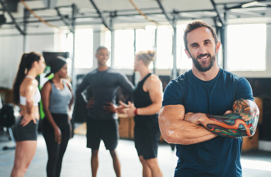 Happy man, portrait and arms crossed in gym with trainer, exercise class and wellness. Person, fitness instructor or worker at health club, smile and confident with pride for training session