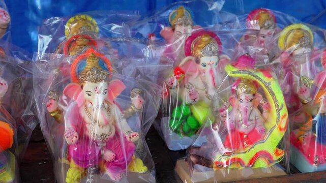 Small Lord Ganesha idols wrapped in plastic on street vendor cart for sale