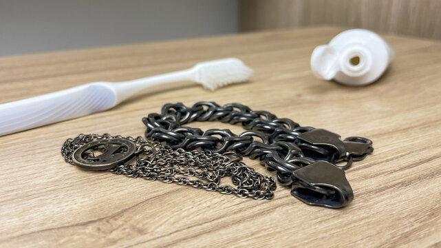 Tarnished silver chains lie next to toothpaste and a toothbrush. A home method for removing tarnish and restoring shine to jewelry.