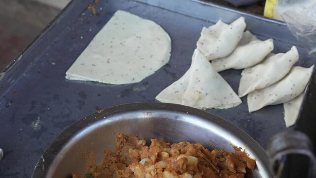 Preparing raw samosa with potato stuffing and dough wrappers on street food stall
