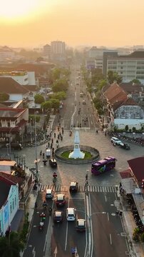 Tugu Jogja monument and city traffic glowing during golden sunset