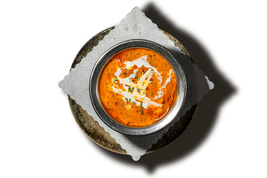 Chicken tikka masala curry with cream swirl and ginger in steel bowl, isolated, top view