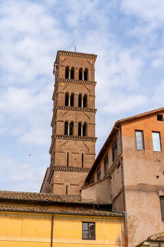 Ancient Roman bell tower with arched windows and colorful mosaic details against sky