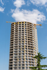 Modern high-rise building under construction with cranes against a blue sky © k_samurkas