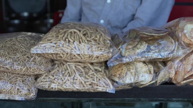 Transparent plastic packets filled with crispy savory sev snacks displayed at a shop