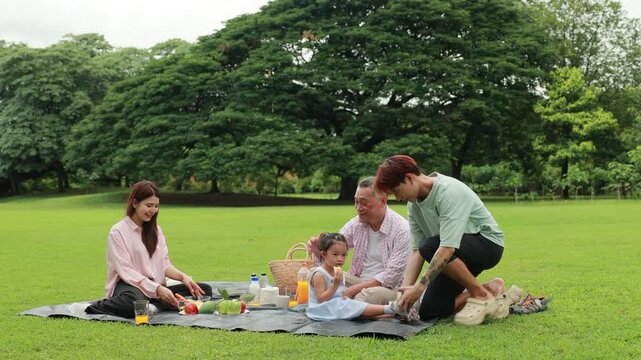 food and drinks. Happy Asian family having fun time on picnic at city nature park, outdoor activitie