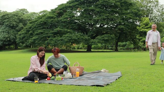 food and drinks. Happy Asian family having fun time on picnic at city nature park, outdoor activitie