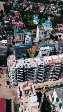 Aerial footage of residential construction surrounded by existing apartment buildings and rooftops, showing the transformation of a dense urban neighborhood.