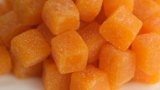 Female hand taking Orange cubes creatine gummies, close up