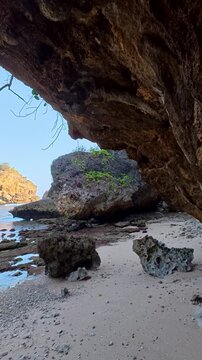 Sea cave opening frames secluded rocky beach and coastal blue water