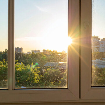 Bright morning sun rays shining through a dirty window glass