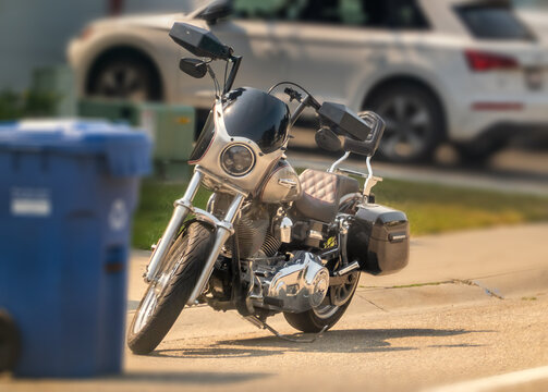 Calgary, Alberta, Canada. September 18, 2026. A parked cruiser motorcycle on a city street with a blue bin and car in the background.