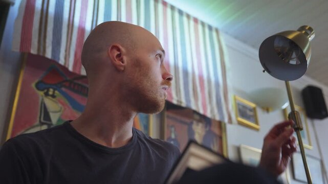 Man Reading Book When Lamp Suddenly Goes Out