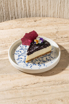 Elegant plated cafe dessert featuring berry cheesecake on a rustic travertine stone table