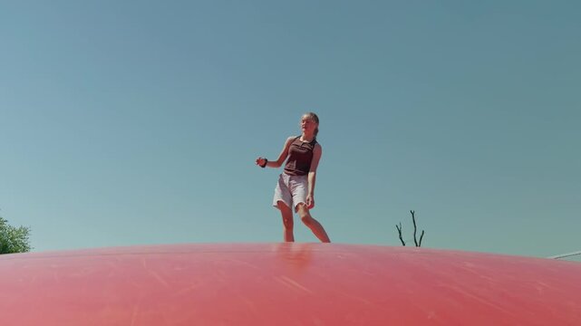A girl does a handstand on a trampoline outdoors summer