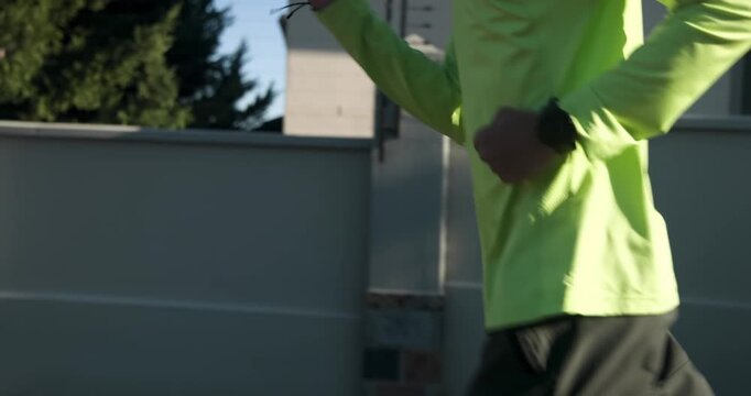 Lifestyle videos outdoor of people doing activities, running outdoors, man in bright green shirt exe