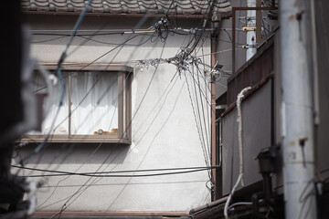 Obraz premium Window and tangled cables on a plaster wall of an old Japanese house, Osaka
