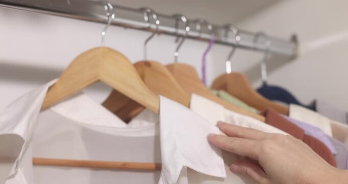 Clothing items hanging on a rack with wooden hangers, apparel display.
