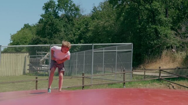 A boy falls dawn onto his back on a trampoline slow motion