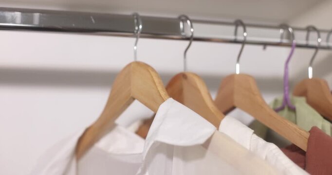 Clothing items hanging on a rack with wooden hangers, apparel display.
