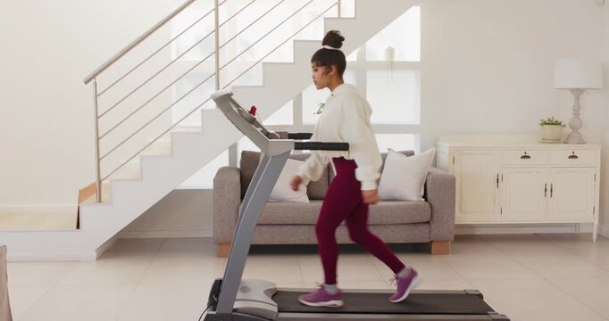 Running on treadmill at home, woman exercising in living room under stairs