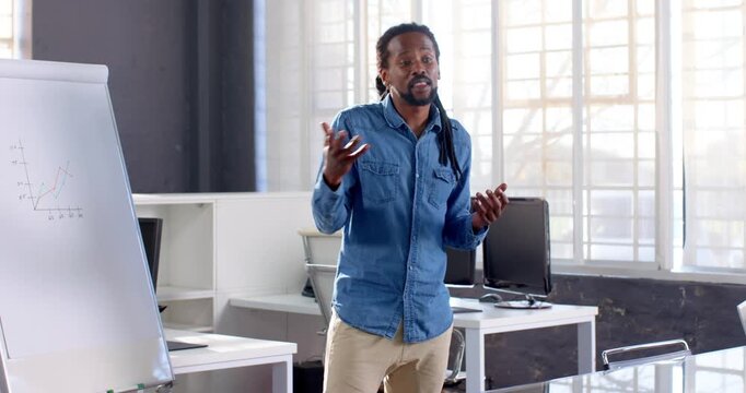 African American man presenting business graph on flip chart in modern office