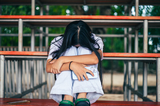 anxious worried teen girl with her smartphone as a conceptual backdrop for cyberbullying social media trauma, teenager mental health crisis, depression and panic attack