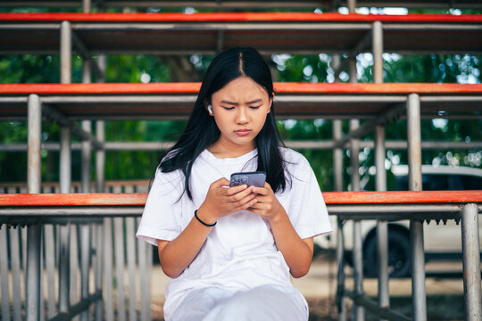 anxious worried teen girl with her smartphone as a conceptual backdrop for cyberbullying social media trauma, teenager mental health crisis, depression and panic attack
