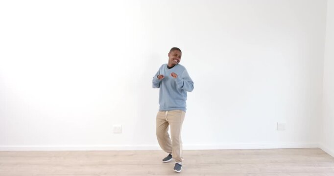 Young boy dancing joyfully in casual outfit against white wall indoors