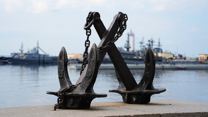 Old ship anchors with chains on the pier against warships background © Семён Прудий