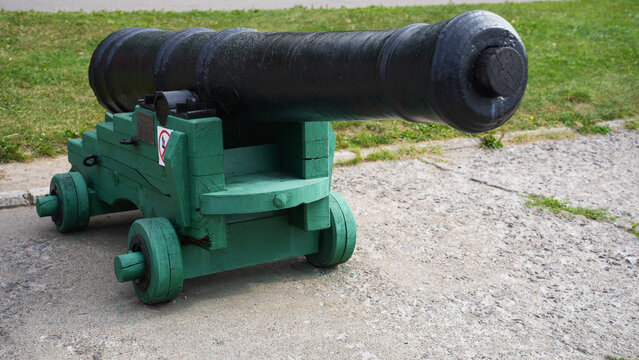 Old black cannon on green wooden carriage outdoors