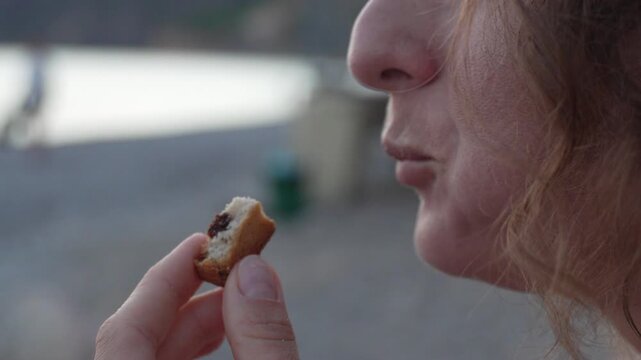 Macro pastry eating by a woman near a calm seaside. Macro close up shot.