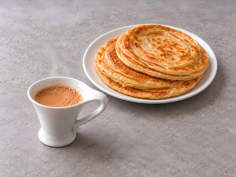 Stack of Golden Flaky Parathas with Creamy Milk Tea