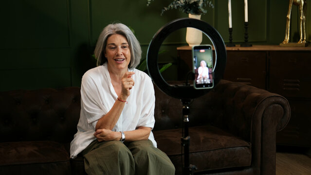 Mature woman creating content and recording video for social media with a smartphone and ring light