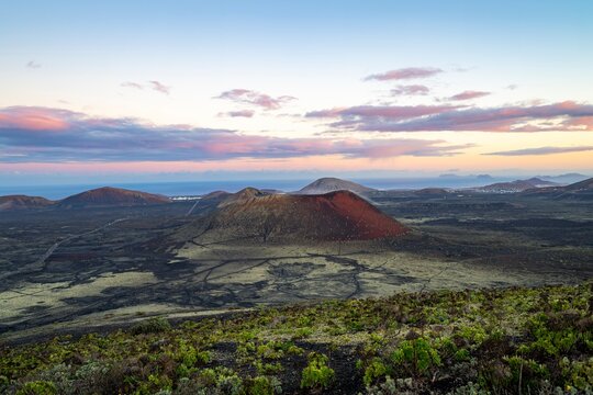 Picturesque volcanic landscape with volcanic craters and lava fields at sunrise, Caldera Colorada volcano, Los Volcanes Natural Park, Lanzarote, Canary Islands, Spain