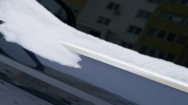 fresh white snow lying on dark car window molding close up, snow-covered side door and mirror of dark automobile after snowfall, macro view of fresh snow layer on black vehicle bodywork in winter