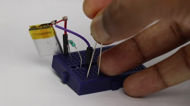 Breadboard circuit with lithium polymer battery and resistor showing the red LED glow as it is connected to the breadboard slot