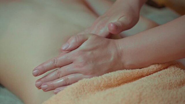 Lymphatic drainage belly massage: hands of a professional masseur applying oil and performing a modeling wellness spa procedure on a woman.