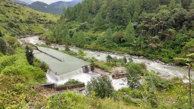 Scenic Mountain River Flowing Beside Concrete Weir in Lush Green Hills