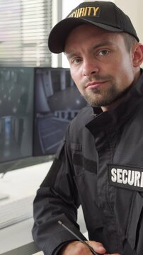 Security officer monitoring surveillance cameras in control room. Guard in uniform watches live feeds at workstation, supporting safety and access control. Visual security and safety concept.