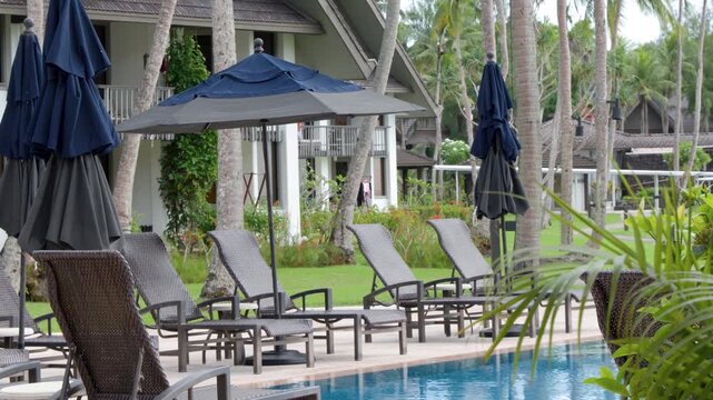 A serene tropical resort with palm trees swaying gently, providing a tranquil escape with beautiful pool area and comfortable lounge chairs.
