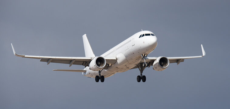 The plane lands, passenger airliner. The plane lands. A white plane flies in storm clouds, preparing to land at the airport