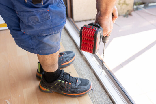 Handwerker bohrt bei der Fenstermontage L&ouml;cher in den Rahmen, Installation einer Terrassent&uuml;r bei einer Hausrenovierung