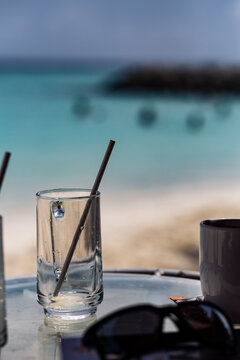 Empty drinking glasses with straws on a refreshment drink on a tropical beach summer background