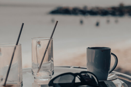 Empty drinking glasses with straws on a refreshment drink on a tropical beach summer background