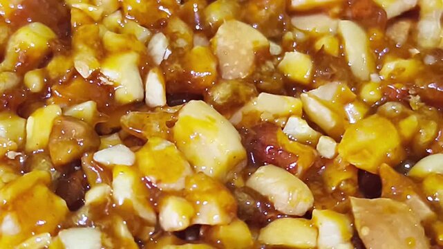macro close up view of homemade peanut brittle candy made with crunchy roasted nuts covered in shiny golden sweet caramel sauce texture background for bakery dessert banner food packaging concept