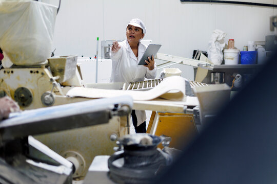 Female supervisor using tablet overseeing food production process