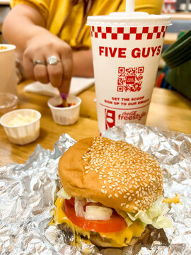 A meal in a Five Guys fast food restaurant with a burger and a cup for a  soda
