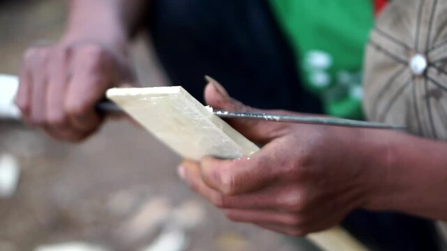 Manufacturing process of a traditional wooden turner for kitchen frying tools by an outdoor worker.