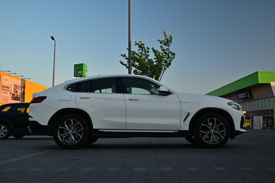 White luxury SUV coupe BMW X4 xDrive30i parked on a city parking lot, side view.
